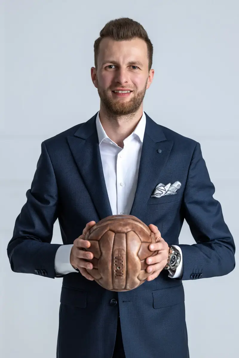 Mateusz Sobczyk, ekspert od nieruchomości, trzymający piłkę nożną.